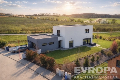 Modern� rodinn� d�m s plochou st�echou, velk� okna, zahrada a p��jezdov� cesta s dla�bou, nach�z� se v klidn� p��rodn� lokalit�