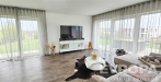 Sv�tl� ob�vac� pokoj s modern� dekorac�, velk�mi okny a kvalitn� podlahou, kter� vytv��� elegantn� a prostorn� obytn� prostor.