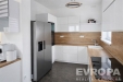 Modern� kuchy� s vestav�n�mi spot�ebi�i, sv�tl�mi sk���kami a d�ev�nou pracovn� deskou, dopln�n� velkou americkou lednic�.