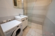Koupelna s modern� dla�bou, sprchov�m koutem a vestav�n�m umyvadlem, prostor pro pra�ku, sv�tle �ed� obklady vytv��ej� elegantn� vzhled.