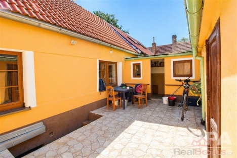 Prostorn� dvorek s dla�bou, venkovn�m n�bytkem a �lutou fas�dou nab�z� p��jemn� venkovn� posezen�.