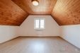 Podkrovn� m�stnost s d�ev�n�m oblo�en�m stropu a lamin�tovou podlahou, sv�tl� m�stnost s velk�m oknem a modern�m vyt�p�n�m.