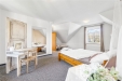 Prostorn� lo�nice s kobercem, rustik�ln�m d�ev�n�m n�bytkem a velk�mi okny, kter� zaji��uj� sv�tl� interi�r, ide�ln� pro pohodln� bydlen�.