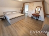 Prostorn� lo�nice s parketovou podlahou, dekorativn�mi tr�my a modern�m n�bytkem. V m�stnosti je velk� man�elsk� postel a zrcadlov� toaletka.