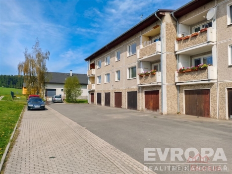 Bytov� d�m s gar�emi, zd�n� konstrukce a balkony. Klidn� lokalita, dob�e udr�ovan� fas�da, prostorn� parkov�n� p�ed budovou.