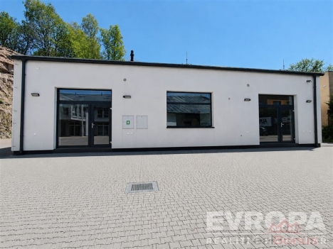 B�l� fas�da komer�n� budovy se t�emi velk�mi okny, modern� design, dla�ba na parkovi�ti, dobrou extern� �dr�bou.