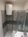 Koupelna s modern� sprchov�m koutem a dla�bou, vybaven� nov�m bojlerem a elegantn�mi obklady, nab�z� praktick� vyu�it� prostoru.