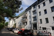 Modern� bytov� d�m, rekonstruovan� exteri�r, b�l� fas�da, velk� okna, klidn� reziden�n� ulice, parkov�n� p�ed budovou.