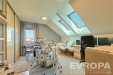 Podkrovn� pracovna s d�ev�n�m n�bytkem, parketovou podlahou a st�e�n�mi okny, sv�tlo pronik� do m�stnosti, modern� design.