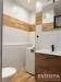Modern� koupelna s dla�bou a d�ev�n�mi obklady, vybaven� umyvadlem s �lo�n�m prostorem a pra�kou, sv�tl� a funk�n� design.