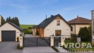 Modern� rodinn� d�m s elegantn� fas�dou, velk� okna a upraven� zahrada, nach�zej�c� se v klidn� oblasti s gar�� a dl�d�n�m p��jezdem.