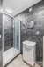 Modern� koupelna s �edou dla�bou, sprchov�m koutem a b�lou umyvadlovou sk���kou, elegantn� kruhov� zrcadlo zdob� ze�.