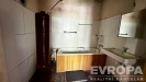 Koupelna s d�ev�n�m obkladem vany, b�l�mi dla�dicemi a star��m bojlerem, vy�aduj�c� rekonstrukci pro modern� vzhled.