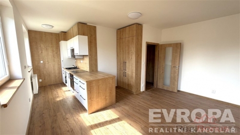 Kuchy� s modern�mi spot�ebi�i, parketovou podlahou a vestav�n�mi sk��n�mi, sv�tl� d�ky velk�m okn�m, ide�ln� pro rodinn� bydlen�.