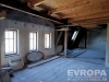 Podkrovn� prostor s d�ev�n�m tr�mov�m stropem, velk�mi okny a p�vodn� podlahou, p�ipraven� k rekonstrukci, nab�zej�c� rustik�ln� charakter.