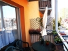Balk�n s venkovn�m posezen�m, plastov�m stolem a �idlemi, v�hled na m�sto, oran�ov� om�tka, dekorativn� rostliny v truhl�c�ch, modern� design.