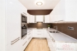 Modern� kuchy� s b�l�mi sk���kami, vestav�n�mi spot�ebi�i a parketovou podlahou. Sv�tl� prostor s modern�m osv�tlen�m a elegantn�m designem.