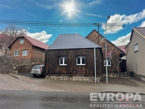 Venkovn� pohled na rekonstruovan� d�m s d�ev�n�m obkladem, plechovou st�echou a plastov�mi okny, situovan� na klidn� ulici