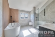Modern� koupelna s velk�mi okny a p��rodn�mi materi�ly, jako je d�evo a elegantn� dla�ba, vytv��� sv�tl� a prostorn� prostor.