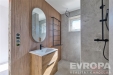 Koupelna s modern�m designem, d�ev�n� obklady, kamenn� dla�ba, velk� zrcadlo a sprchov� kout s �ern�m kov�n�m.