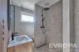 Modern� koupelna s dla�bou, sprchou a d�ev�n�m umyvadlov�m stolem. Velk� okno poskytuje dostatek sv�tla, elegantn� armatury dod�vaj� stylov� vzhled.
