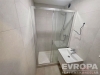 Modern� koupelna s b�l�mi obklady, sprchov�m koutem a z�v�sn�m umyvadlem. Sv�tl� interi�r dod�v� eleganci a jednoduchost.