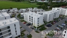 Novostavba bytov�ho domu s modern� fas�dou v klidn� reziden�n� �tvrti, obklopen� zelen� a parkovi�t�m.