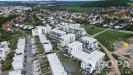 Pohled na modern� bytov� komplex s plochou st�echou, obklopen� zelen� a upraven�mi p��mi z�nami, ide�ln� pro klidn� bydlen� bl�zko m�sta.
