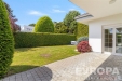 Zahrada s dl�d�nou terasou, obklopen� �iv�m plotem, nab�z� soukrom� a prostor pro relaxaci. Pe�liv� udr�ovan� tr�vn�k a modern� styl fas�dy.
