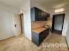 Kompaktn� kuchy� s parketovou podlahou, modern�mi tmav�mi sk���kami a sv�tlou dla�bou na st�n�ch, ide�ln� pro efektivn� va�en�.