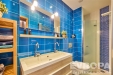 Modern� koupelna s modr�mi dla�dicemi, d�ev�nou sk���kou a prosklen�m sprchov�m koutem nab�z� sv�� a elegantn� styl.