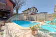 Venkovn� terasa s baz�nem, obklopen� kamennou dla�bou, nab�z� relaxa�n� prostor s modern�m zast�e�en�m, ide�ln� pro letn� dny.